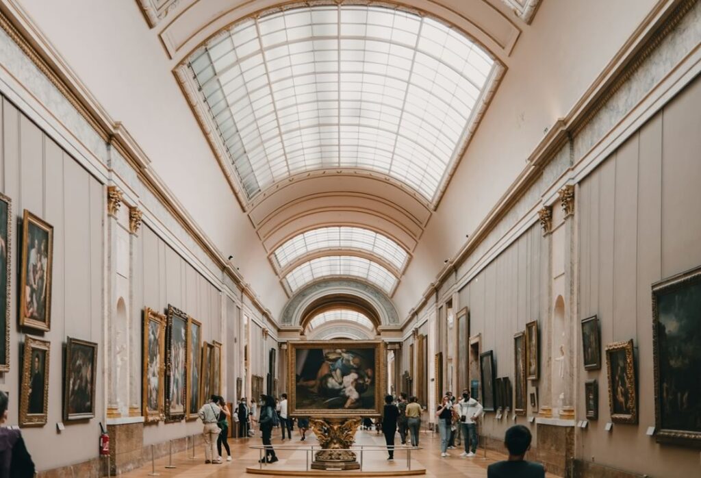 Interior do Museu do Louvre, pessoas olhando as obras de arte.