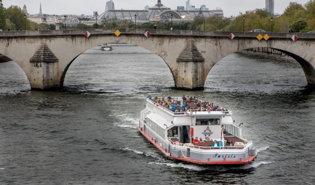 Passeio de Barco no Sena: Vale a Pena Fazer? 10 Barco de turismo passando sob uma ponte histórica no Rio Sena em Paris