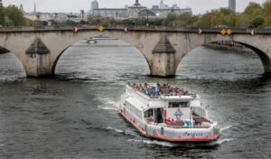 Barco de turismo passando sob uma ponte histórica no Rio Sena em Paris