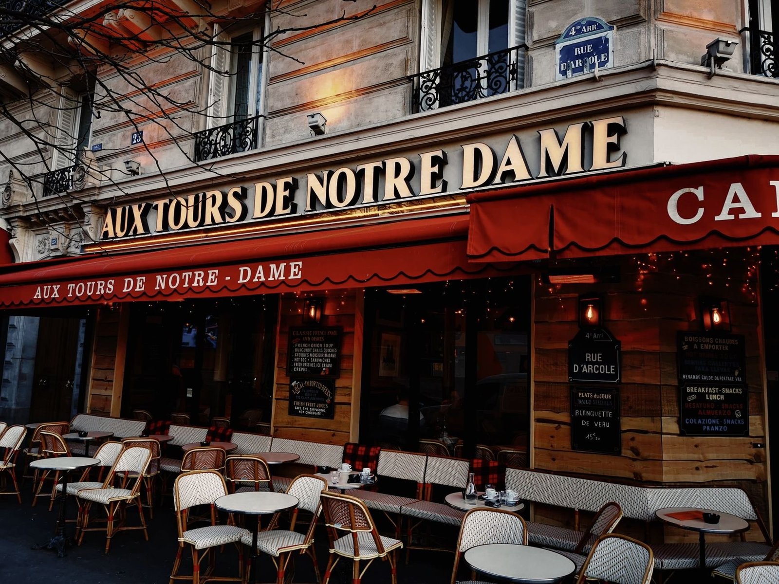 Saint-Germain-des-Prés: Roteiro pelo Bairro Literário de Paris 3 Exterior de café parisiense com iluminação aconchegante e mesas na calçada