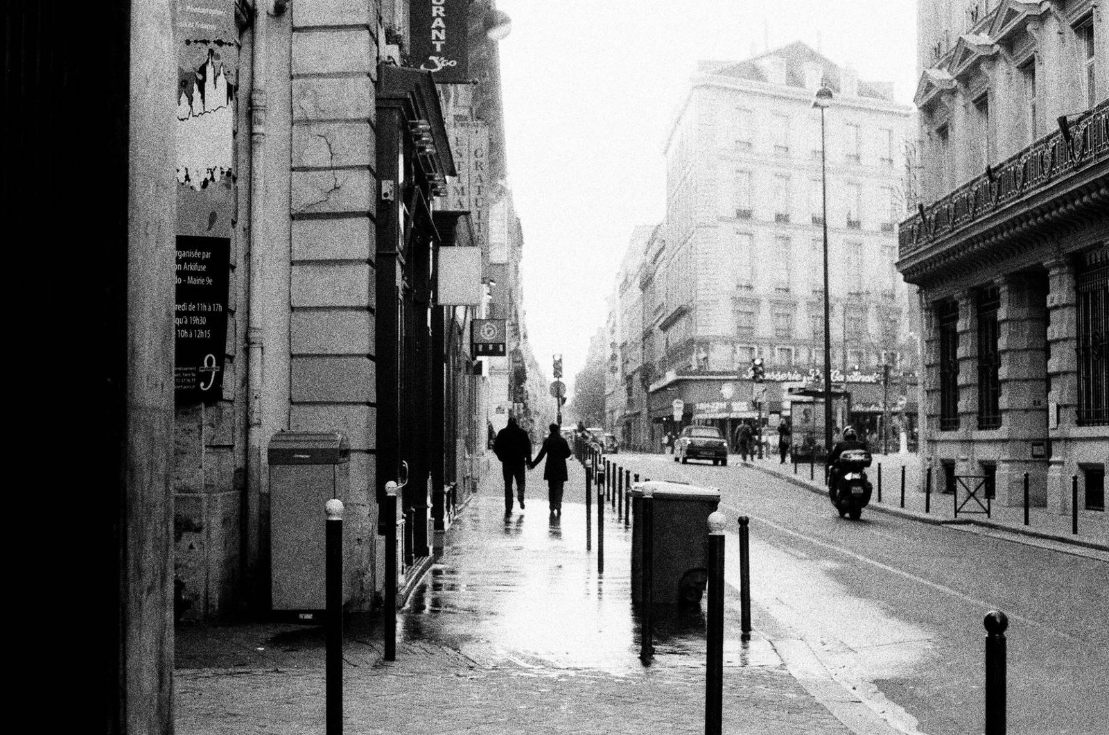 Le Marais Paris: guia do bairro mais charmoso da cidade 4 Casal caminhando de mãos dadas por rua de Paris em dia chuvoso