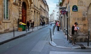 Rua charmosa do bairro Le Marais em Paris, com fachadas históricas e lojas