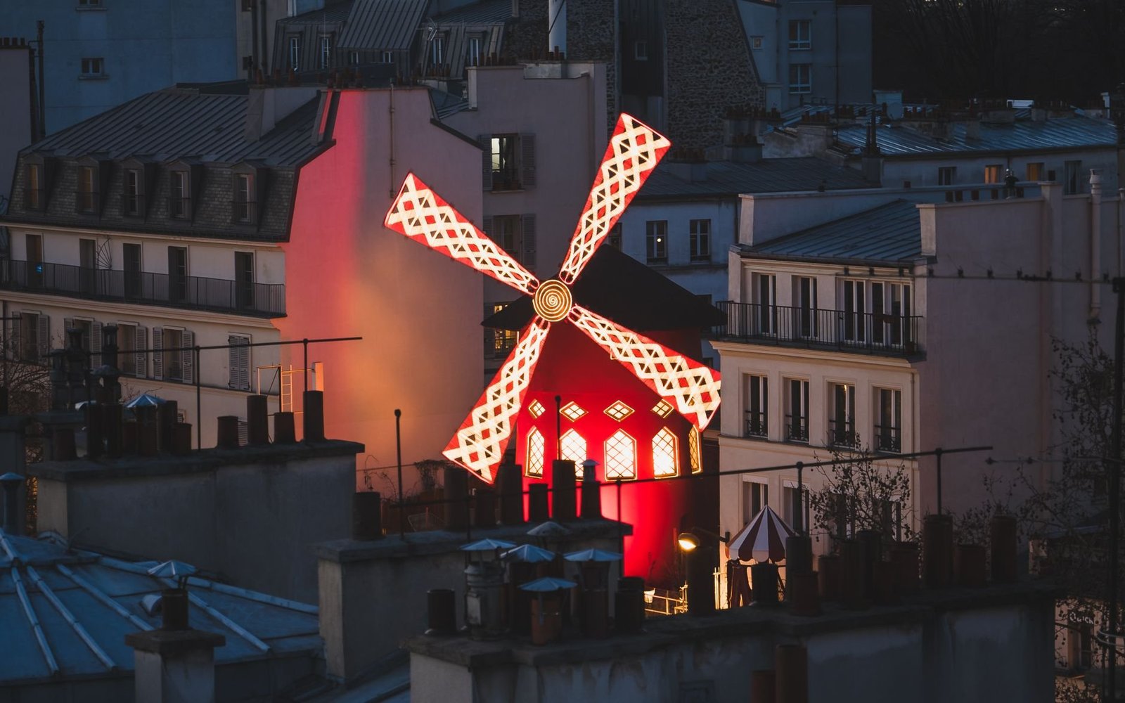 Quartier Pigalle em Paris: o que ver no bairro do Moulin Rouge 2 Moinho vermelho do Moulin Rouge iluminado ao entardecer em Pigalle Paris