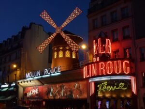 Fachada do Moulin Rouge em Paris com o moinho vermelho iluminado à noite