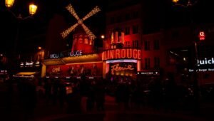 Moulin Rouge iluminado à noite no bairro Pigalle de Paris com moinho vermelho em destaque