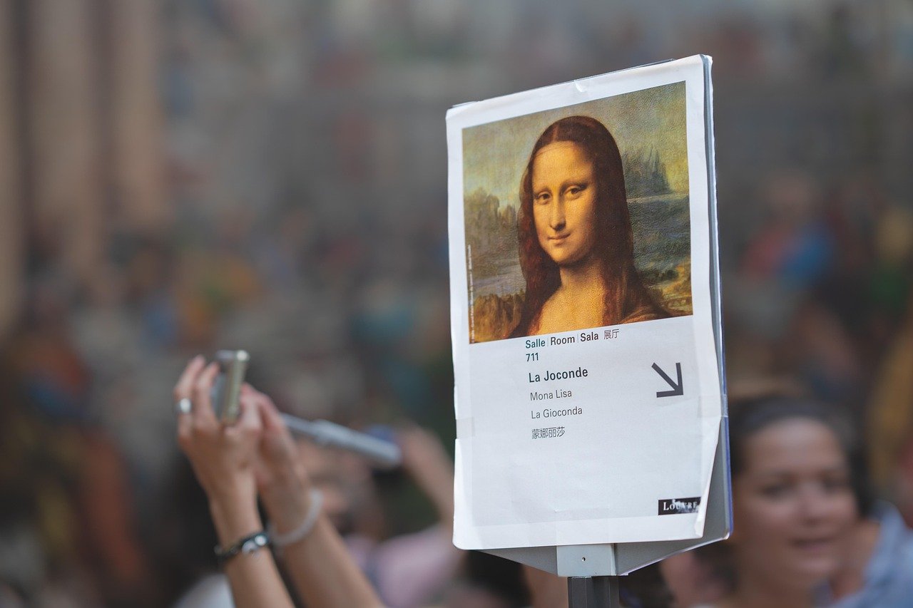 Museu do Louvre: Ingressos, Como Evitar Filas e o Que Ver 3 Placa da Sala 711 indicando La Joconde (Mona Lisa) com multidão fotografando ao fundo