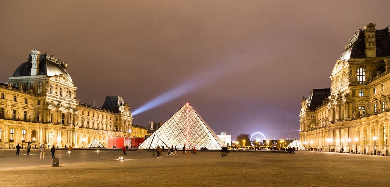 Museu do Louvre: Ingressos, Como Evitar Filas e o Que Ver 2 Pirâmide do Louvre iluminada à noite com o palácio ao redor na Cour Napoléon