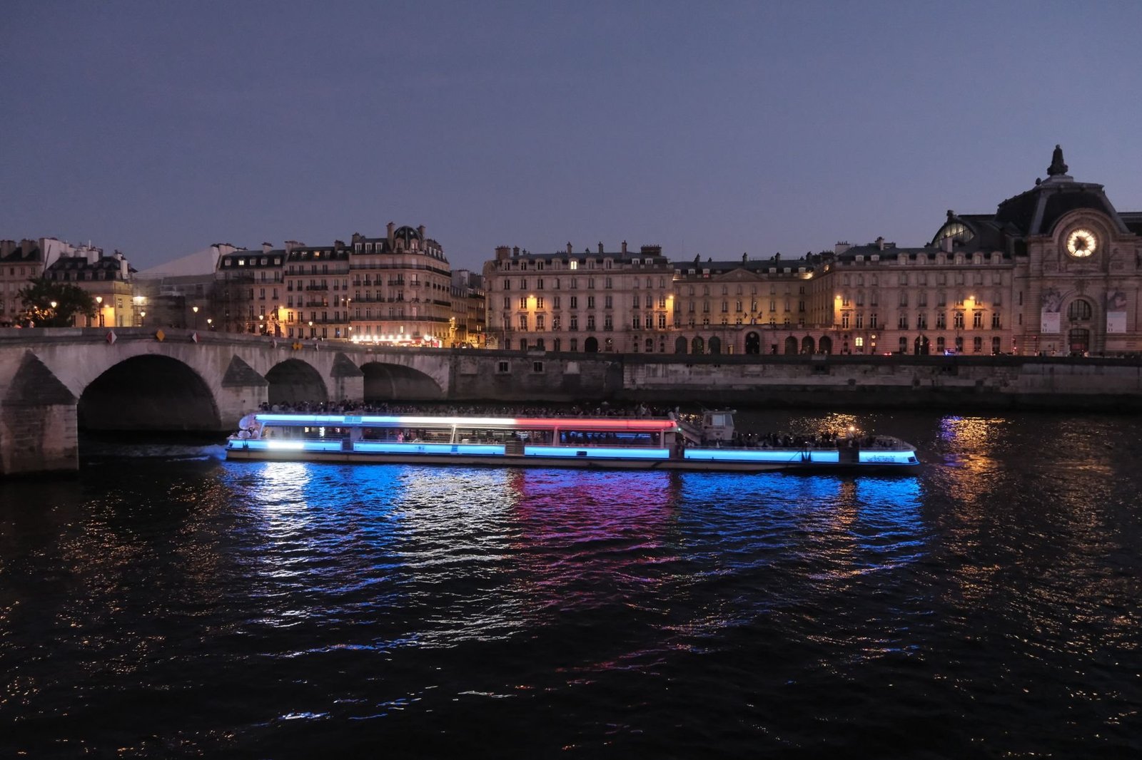 Passeio de Barco no Sena: Vale a Pena Fazer? 3 Barco iluminado navegando pelo Rio Sena à noite perto do Museu d'Orsay