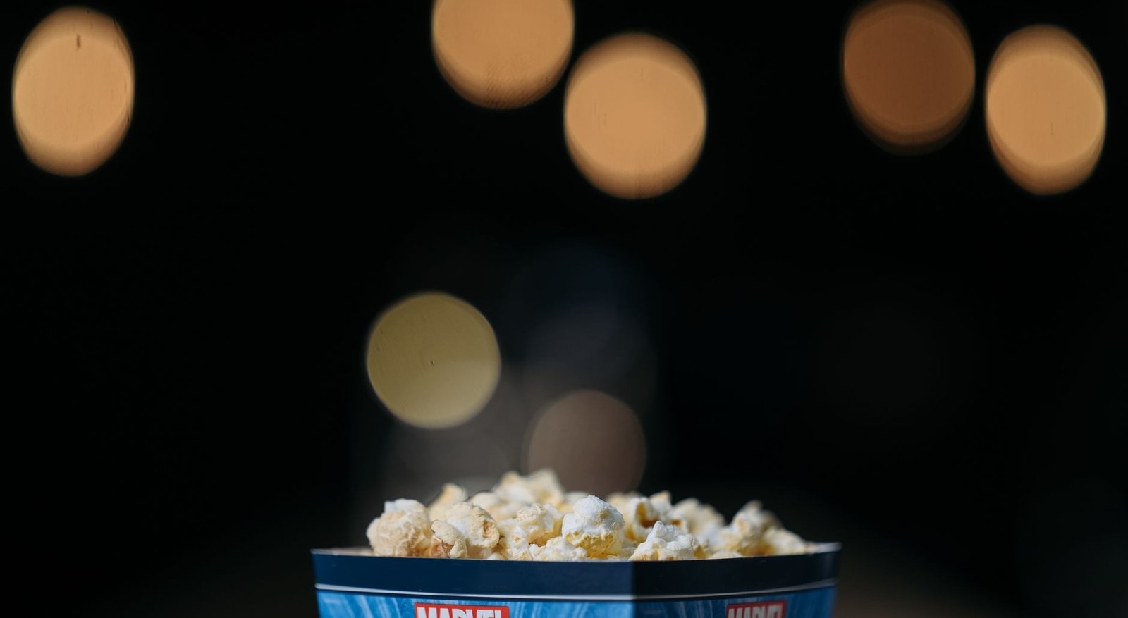 Cinéma en Plein Air 2026 : Cinéma Gratuit en Plein Air au Parc de la Villette (Guide Complet) 3 Pop-corn dans un seau thématique avec un fond flou de cinéma en plein air nocturne