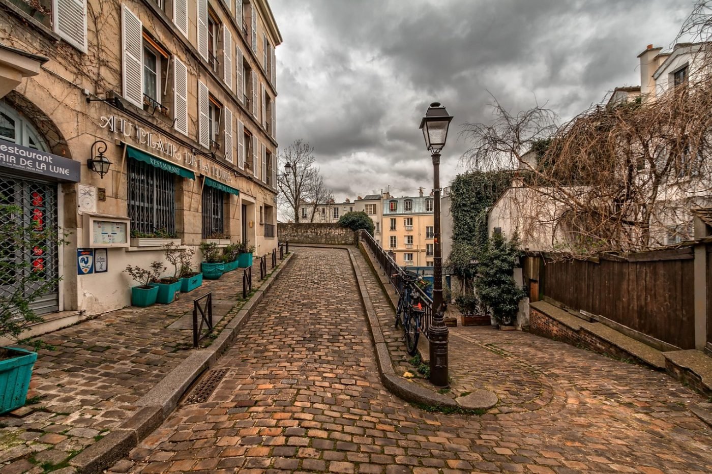 Cemitério de Montmartre: História, Túmulos Famosos e Dicas de Visita 3 Rua de pedras de Montmartre com prédios históricos parisienses