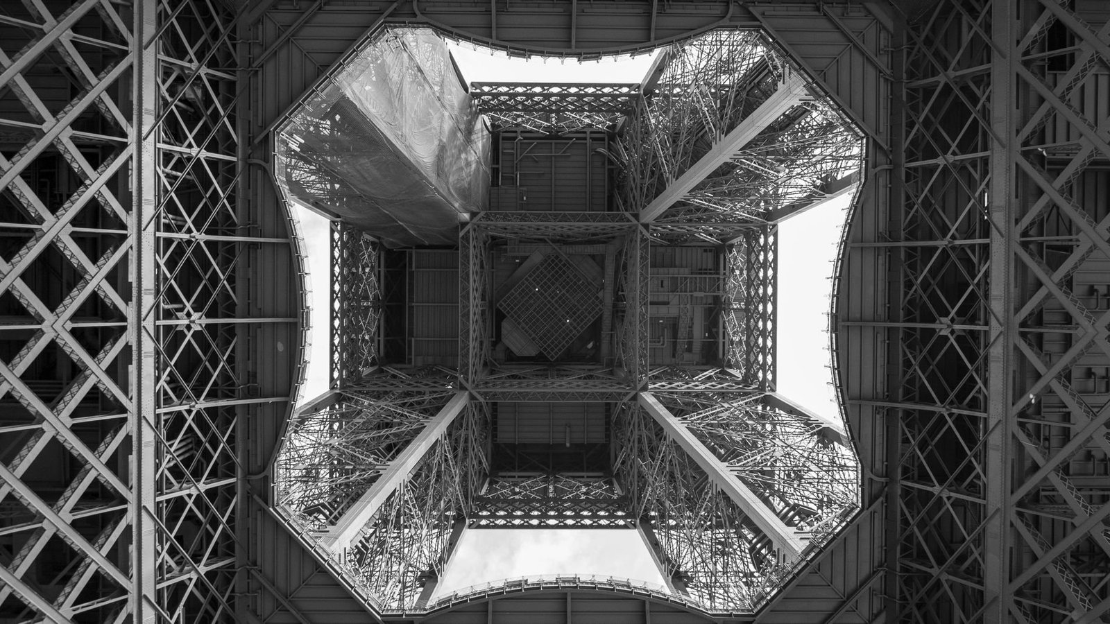 The Story of the Eiffel Tower: From Controversy to the World’s Most Visited Monument 3 Black and white view of the Eiffel Tower’s metal structure from below