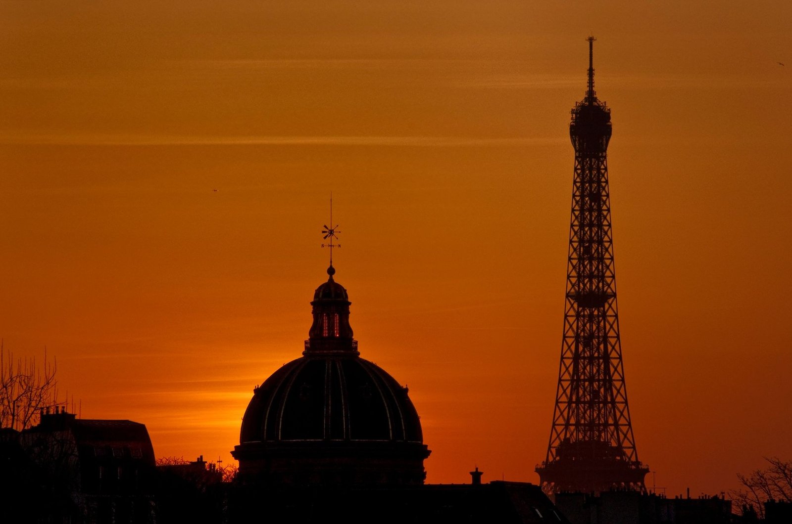 Como Tirar as Melhores Fotos da Torre Eiffel: Guia Completo 4 Silhueta da Torre Eiffel contra o céu alaranjado do pôr do sol
