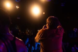 Cantor no palco durante show com plateia e iluminação cênica