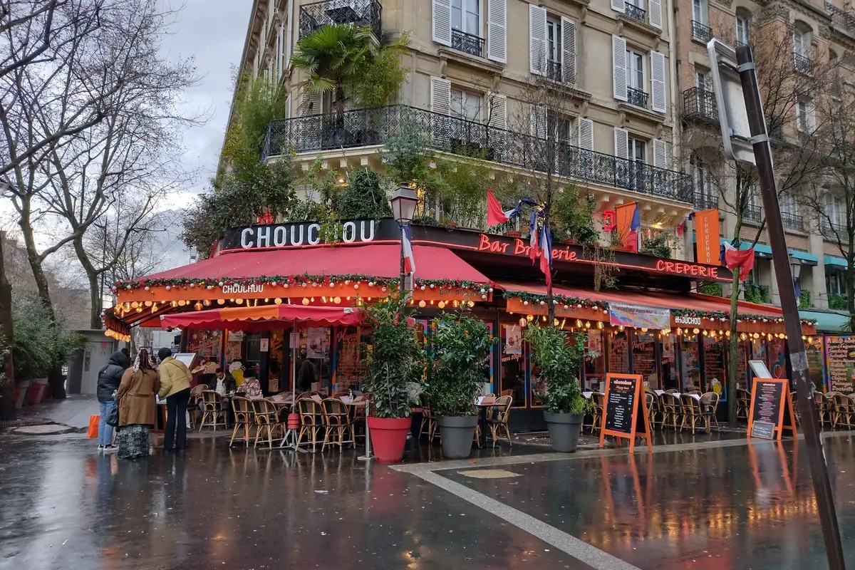 Bastille e Faubourg Saint-Antoine a pé: história e design 3 Café parisiense charmoso com mesas na calçada em dia chuvoso