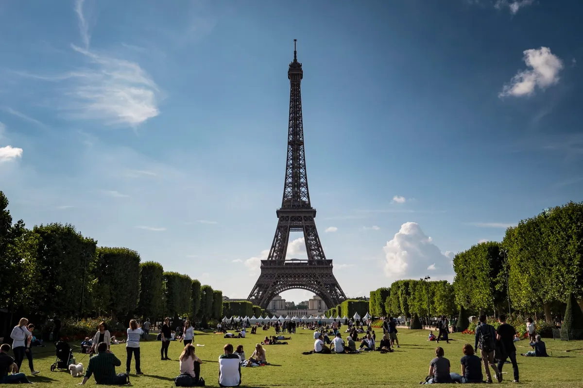 França para famílias: melhores regiões com crianças 1 Família sentada no gramado em frente à Torre Eiffel em Paris